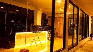 Um hall de hotel moderno com balcão de recepção, área de estar e grandes janelas.