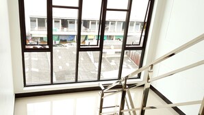 Vista da janela com escadaria metálica que leva a uma varanda.
