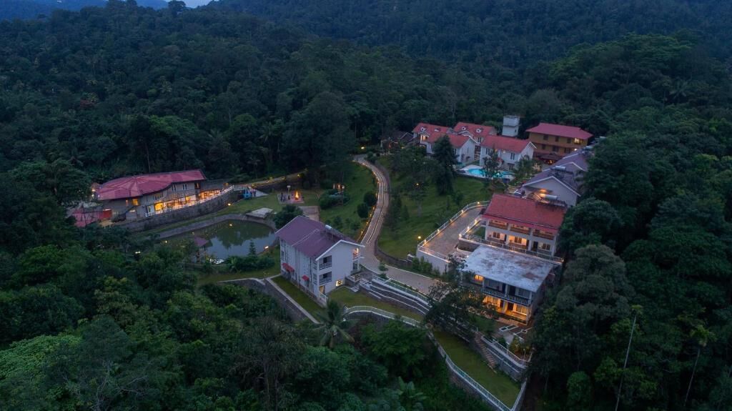 An aerial view of a resort with multiple buildings, a winding road, and lush greenery surrounding the area.