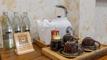 Un vassoio con teiera, tazze, bottiglie, un codice QR per il servizio in camera e una scatola di fazzoletti.