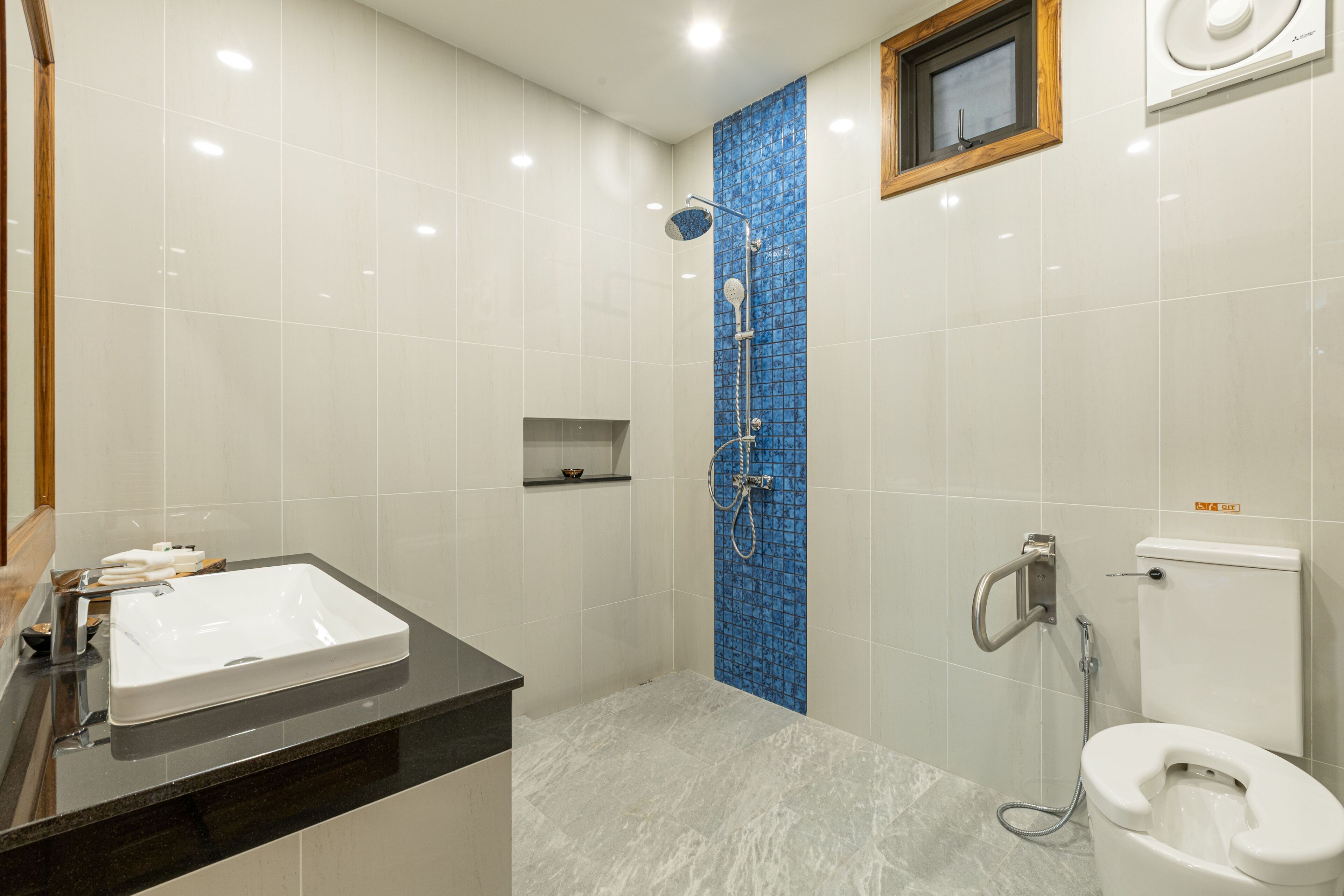 Ein Badezimmer mit einem weißen Waschbecken, einer Dusche mit blauen Fliesen und einer Toilette.