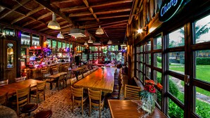 Una zona de bar con mesas y sillas de madera, una barra con diferentes botellas y un cartel que dice 