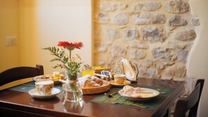 A breakfast table with croissants, bread, a vase with flowers, a basket, and a cup of coffee. - Casale Serena 1912 (Fabro)