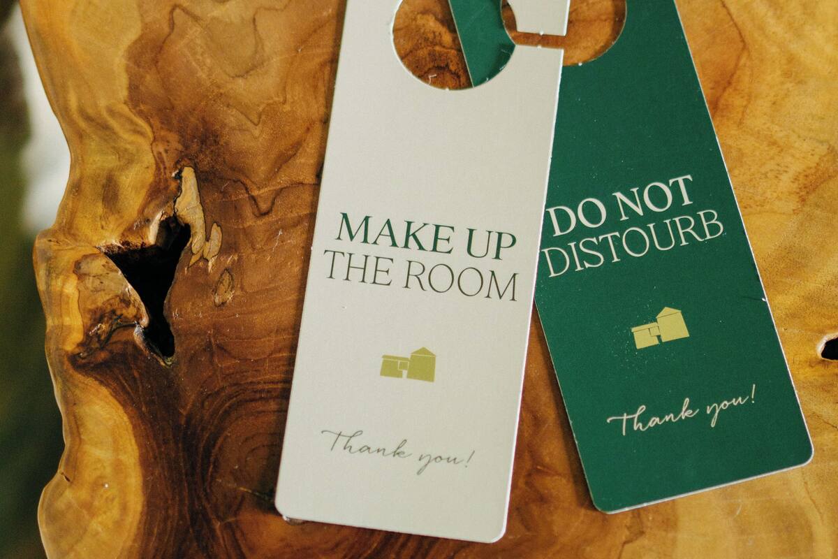 A wooden surface with two tags, one white and one green, with text "MAKE UP THE ROOM" and "DO NOT DISTURB" respectively.