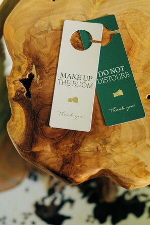 A wooden surface with two tags, one white and one green, with text "MAKE UP THE ROOM" and "DO NOT DISTURB" respectively. - Casale Serena 1912 (Fabro)