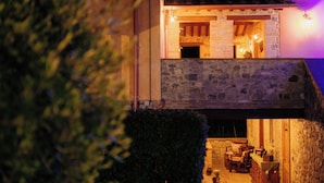 A stone building with a fireplace, outdoor seating, and a view of the surrounding area. - Casale Serena 1912 (Fabro)