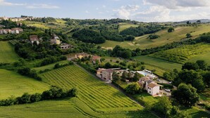 A rural landscape with rolling hills, vineyards, and scattered buildings. - Casale Serena 1912 (Fabro)