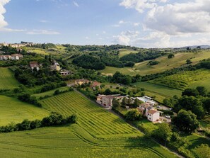 A rural landscape with rolling hills, vineyards, and scattered buildings. - Casale Serena 1912 (Fabro)
