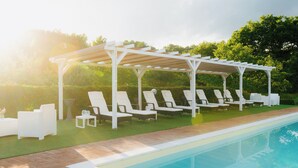 A poolside area with white lounge chairs and a pergola structure. - Casale Serena 1912 (Fabro)