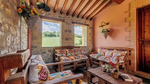 A rustic room with wooden furniture, stone walls, and large windows overlooking a green landscape. - Casale Serena 1912 (Fabro)