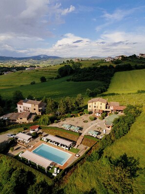 A large estate with multiple buildings, a swimming pool, and surrounding green fields. - Casale Serena 1912 (Fabro)