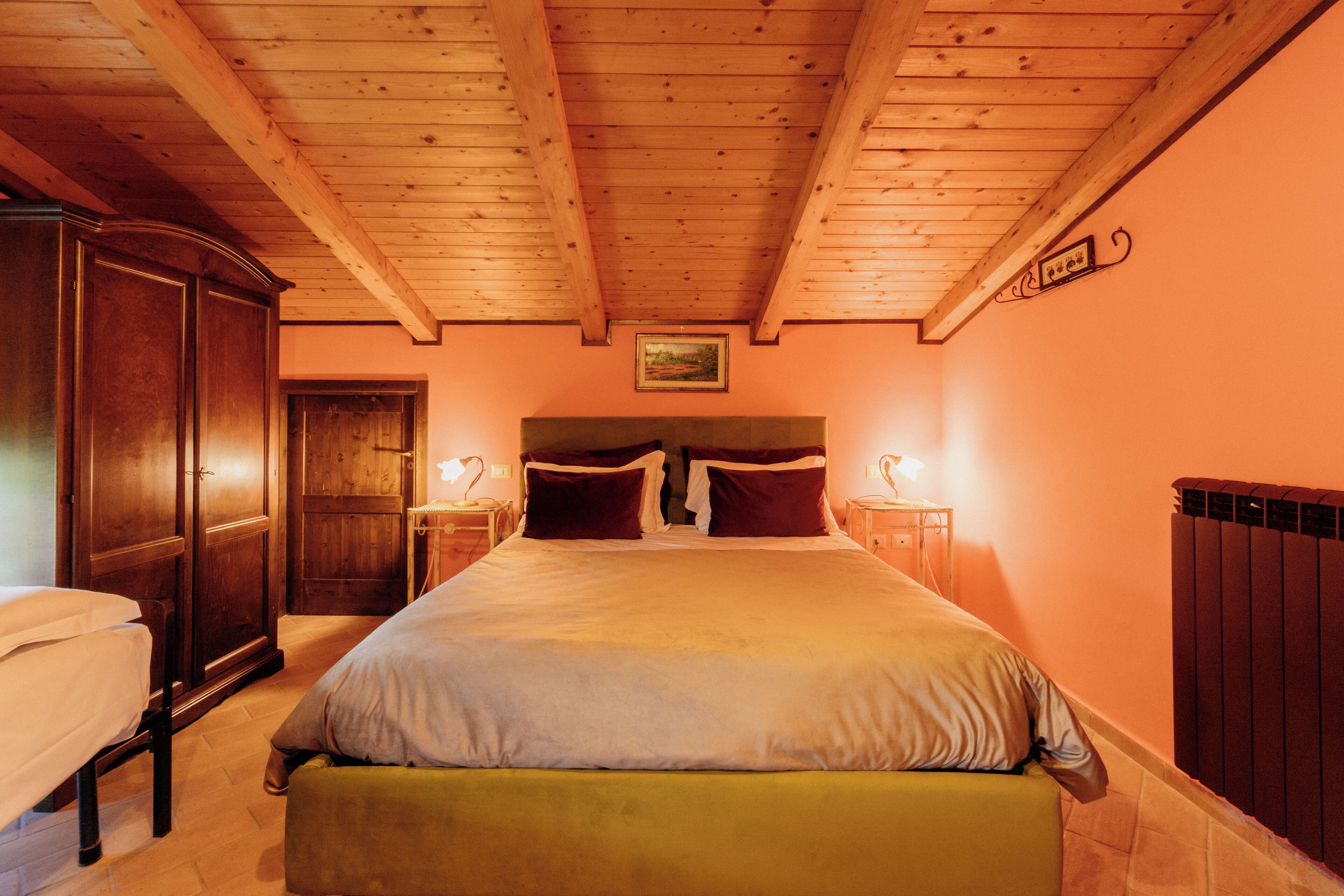 Ein Schlafzimmer mit Holzboden, einem großen Bett mit Kissen, einem Kleiderschrank und Nachttischlampen.