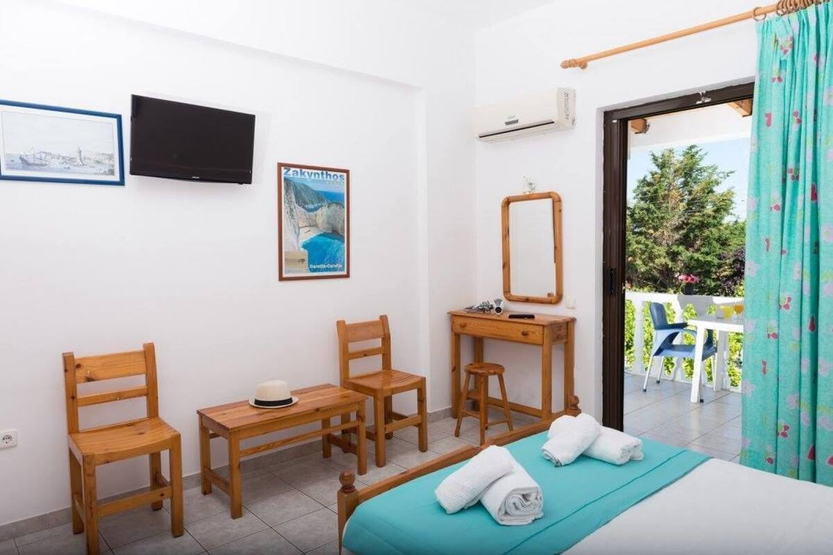 A bedroom with a bed, two wooden chairs, a small table, a mirror, and a poster on the wall.