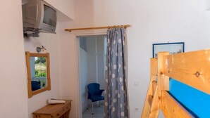A small room with a wooden desk, a chair, a television mounted on the wall, and a door leading to another room. - Studio Stars (Zakynthos)