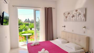 Una habitación de hotel con cama, televisión, un cuadro y vistas a un jardín.