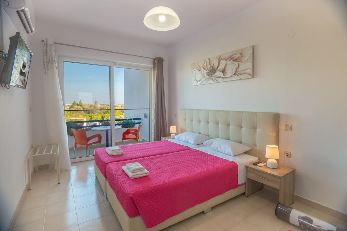 Ein Hotelzimmer mit zwei Betten, einem Balkon und Blick ins Freie.