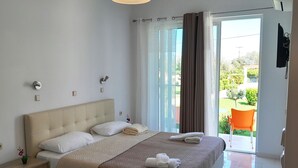 Une chambre à coucher avec un lit, des tables de chevet, une lampe et une vue sur l’extérieur.