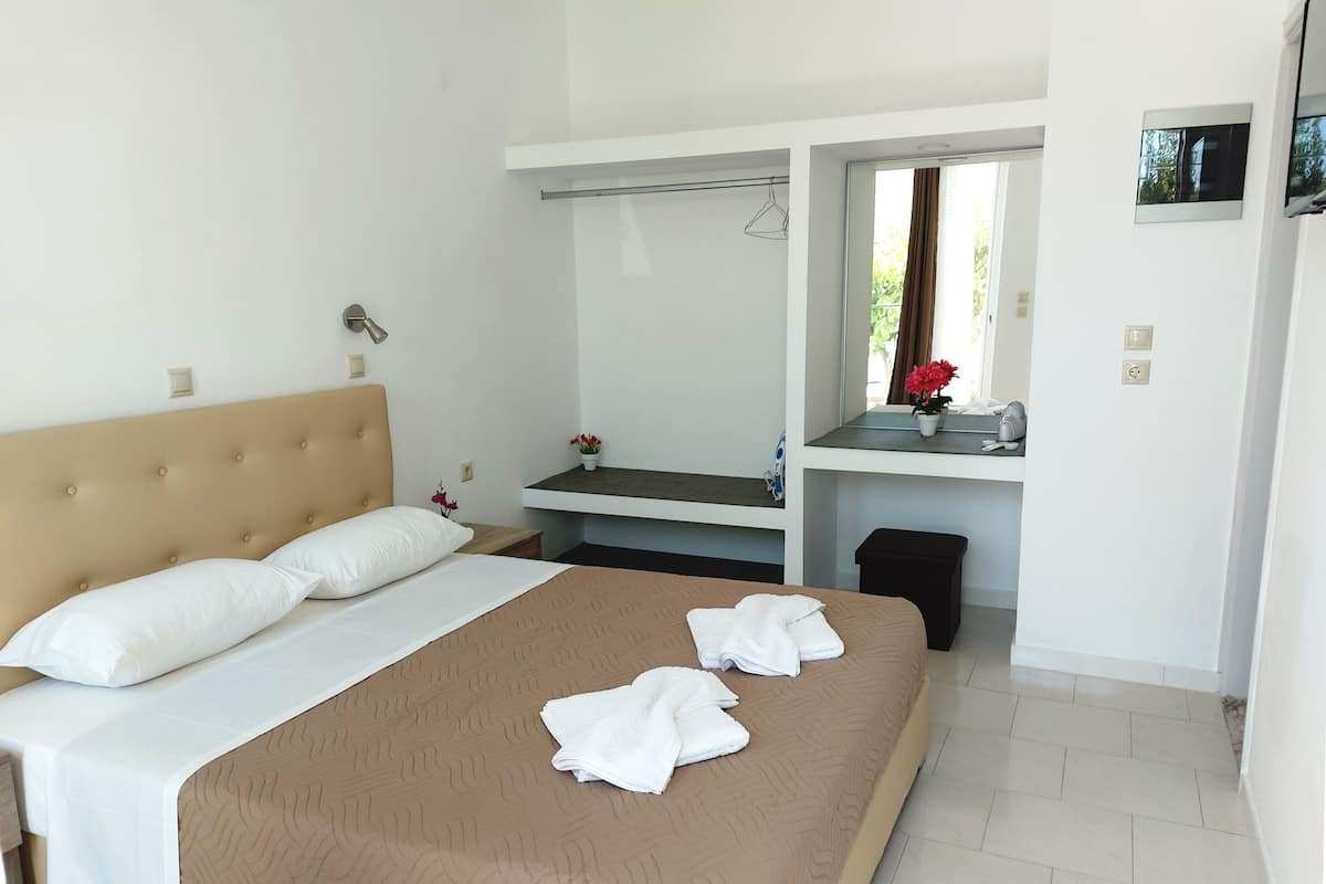 Ein Hotelzimmer mit Bett, Nachttisch, Spiegel und einem kleinen Fenster.