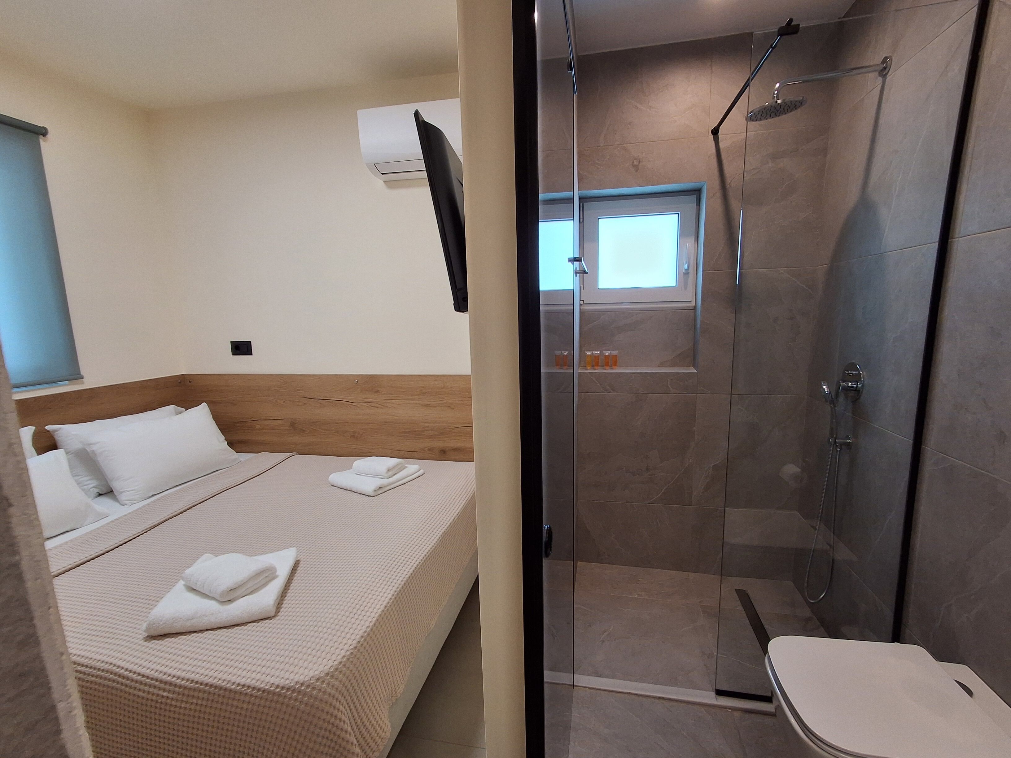 A hotel room with a bed, a shower, and a toilet.