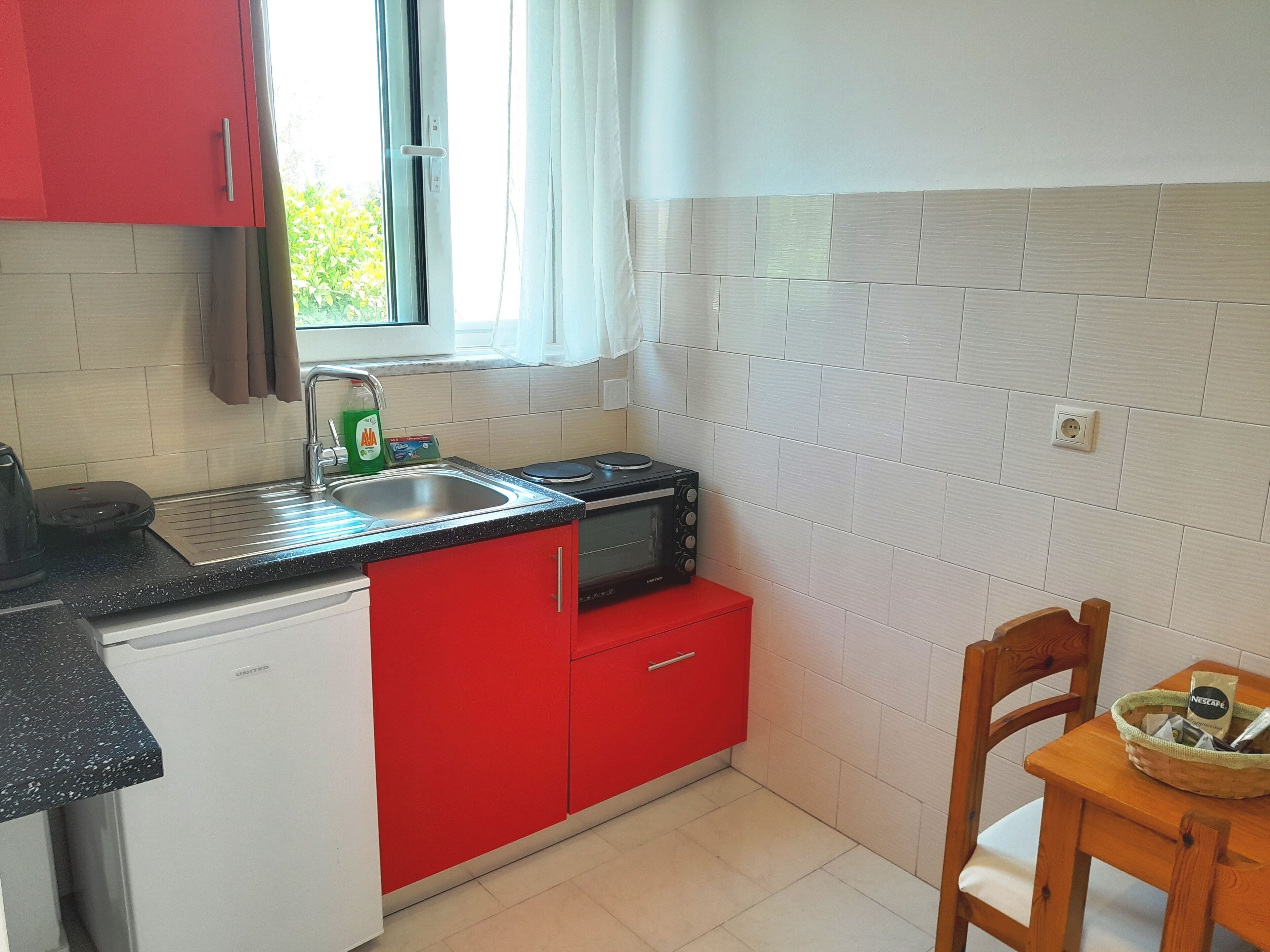 A compact kitchen with a sink, a microwave, and a red cabinet.