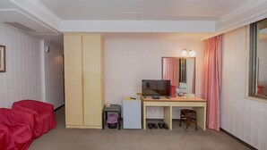 A hotel room with a desk, television, and a wardrobe. - Empire Hotel (Taipei)