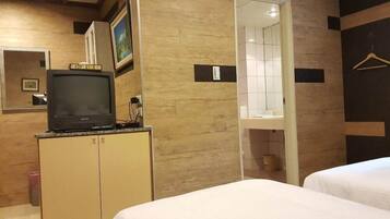 A hotel room with a television on a cabinet, a mirror, and a bed.
