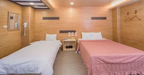A hotel room with two beds, a nightstand with a phone and shoe storage, a mirror, and wooden walls. - Empire Hotel (Taipei)