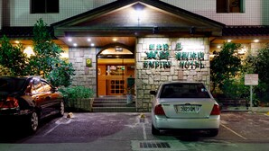 A hotel entrance with a stone facade, a covered entrance, and a parked car in front. - Empire Hotel (Taipei)