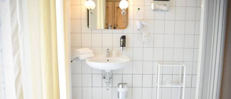A bathroom with a white sink, mirror, and tiled floor.