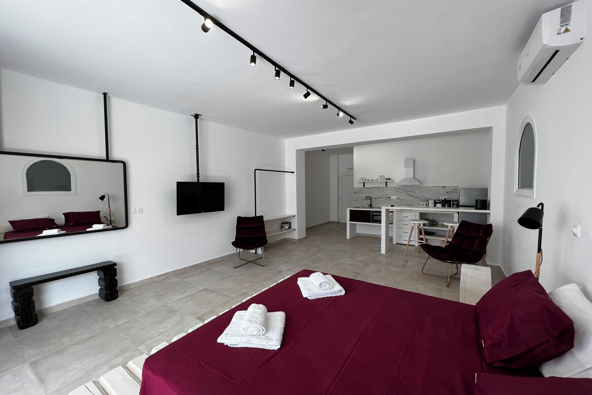 A modern hotel room with a bed, a desk, a chair, a TV, and a mirror.
