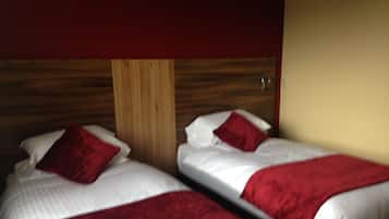 Two beds with red bedding and wooden headboards in a room with a wooden wall panel.