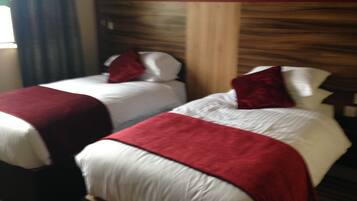 Dos camas con ropa de cama roja y blanca, cabeceros de madera y una alfombra a rayas.