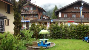 Un patio de hotel con una mesa de picnic, una pequeña fuente y un coche de juguete azul.