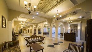 A spacious lobby with high ceilings, ornate chandeliers, and a central seating area with sofas and a coffee table. - Tembo Palace Hotel (Zanzibar Town)