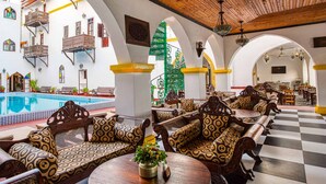 A poolside area with wooden furniture and a checkered floor. - Tembo Palace Hotel (Zanzibar Town)