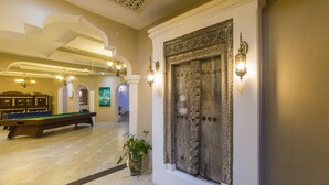 A pool table in a room with a large ornate door and wall sconces. - Tembo Palace Hotel (Zanzibar Town)