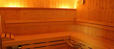 Una sauna con bancos de madera y un balde de madera.