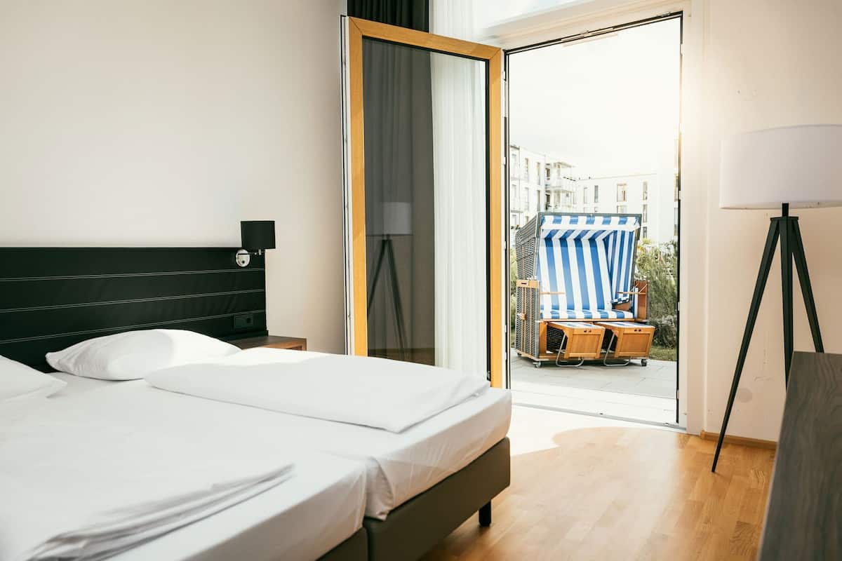 Een hotelkamer met een bed, een bureau, een lamp en uitzicht.