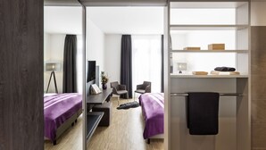 A modern hotel room with a bed, desk, chairs, and a mirror. - Hotel K99 (Radolfzell am Bodensee)