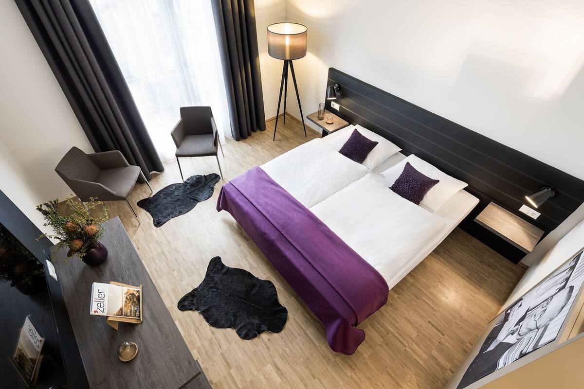 Een moderne hotelkamer met een groot bed, een bureau met een computer, een stoel en een vloerlamp.