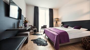 A modern hotel room with a bed, a desk, a chair, a lamp, and a large window.