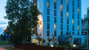 A modern hotel with a blue facade, multiple balconies, and a well-lit entrance. - Hotel K99 (Radolfzell am Bodensee)