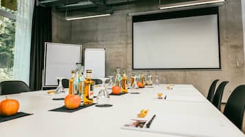 A conference room with a long table, chairs, a projector screen, and a whiteboard.