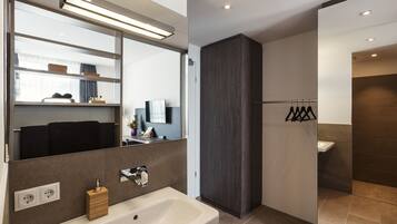 A modern bathroom with a large mirror, a bathtub, a vanity with a sink, and a shower area.