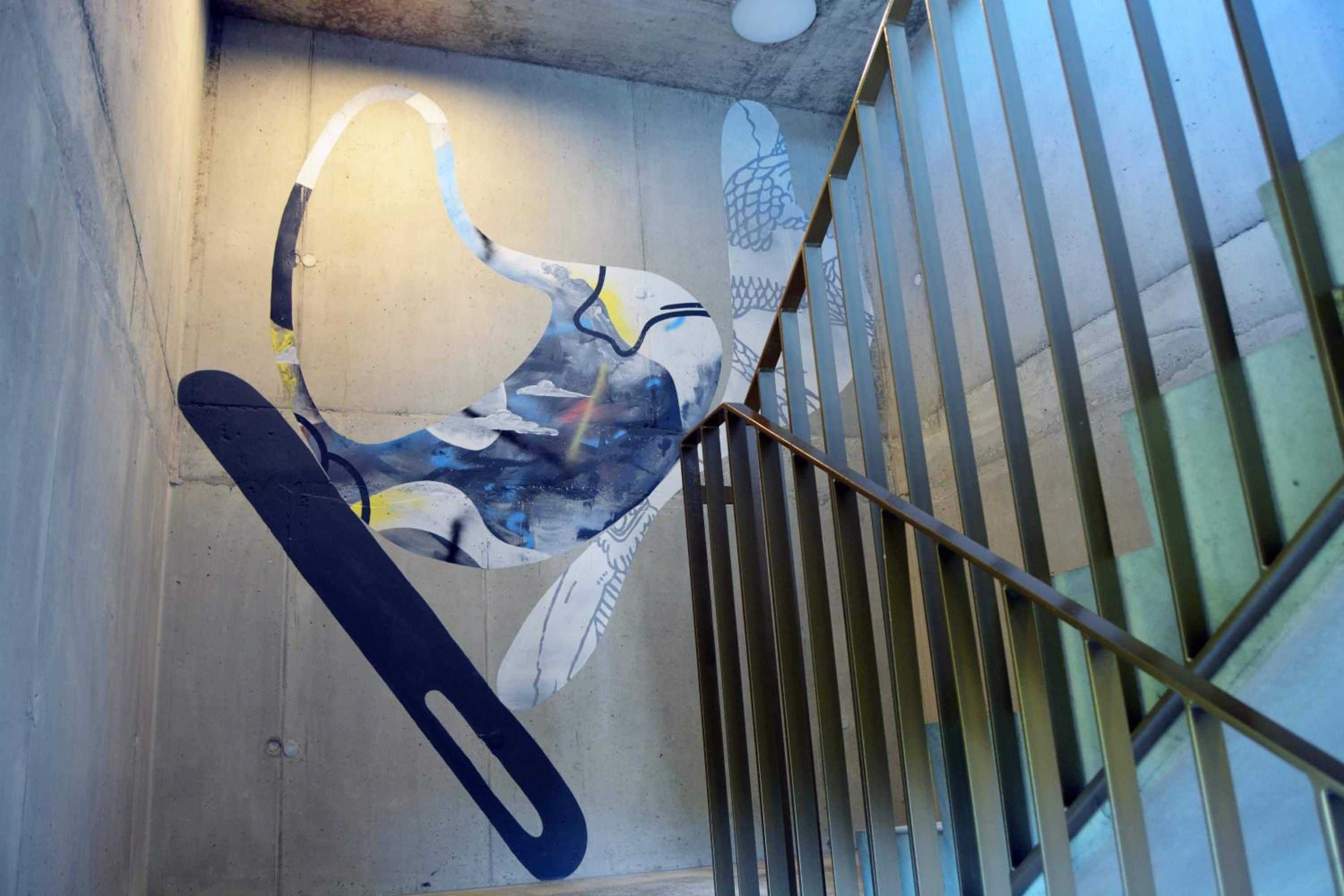 A staircase with metal railings and a wall with a graffiti-style mural.