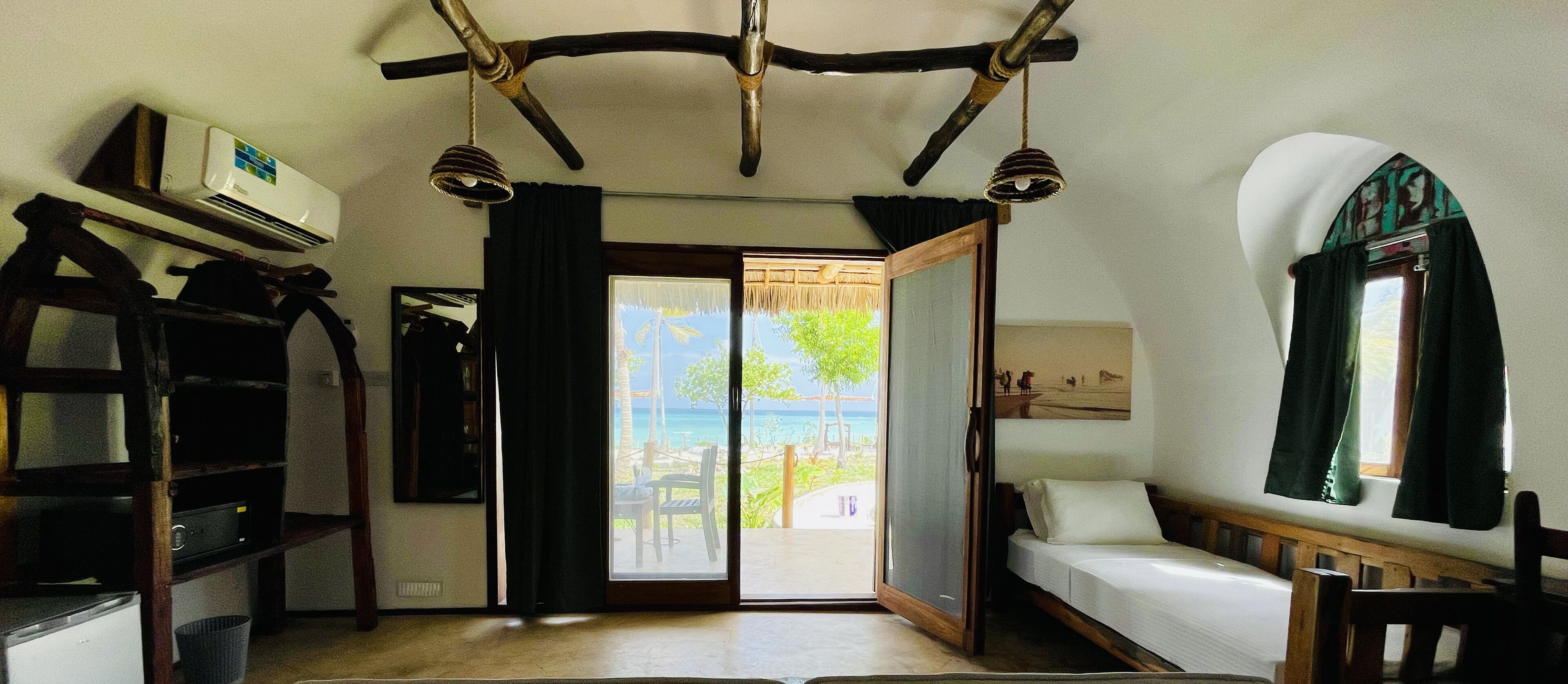 Una habitación con cama, escritorio y vista al mar.