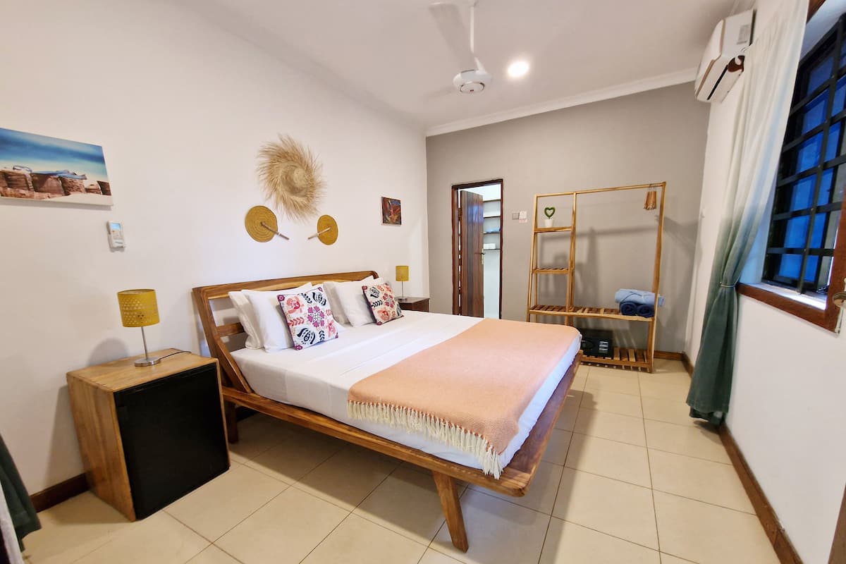 A neatly arranged bedroom with a bed, bedside tables, a wardrobe, and a window with curtains.