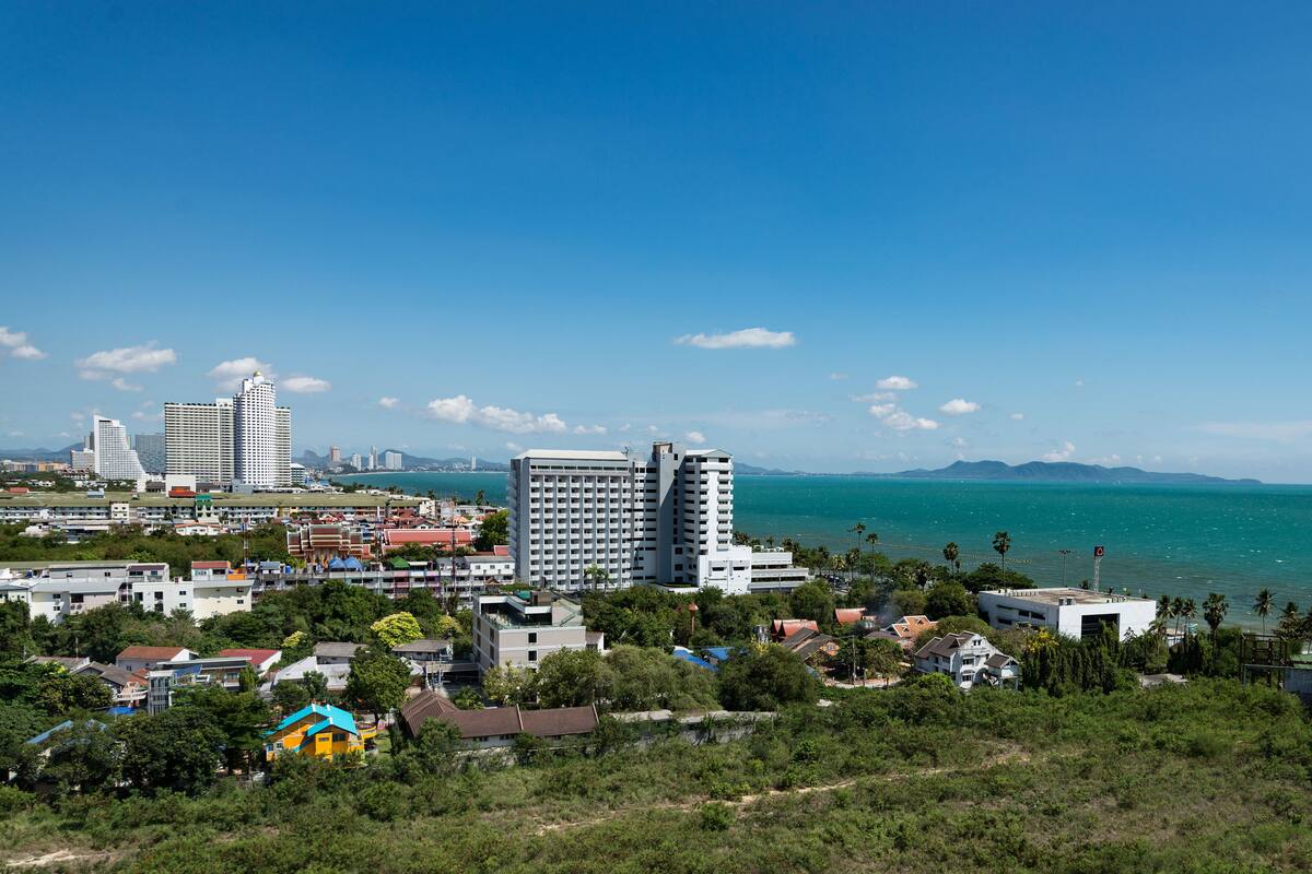 A coastal cityscape with modern buildings, a clear blue sky, and a view of the sea.