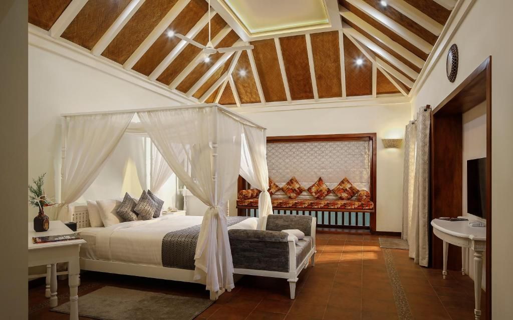 A bedroom with a canopy bed, a sofa, and a television.