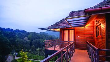 A wooden building with a balcony overlooking a lush valley.